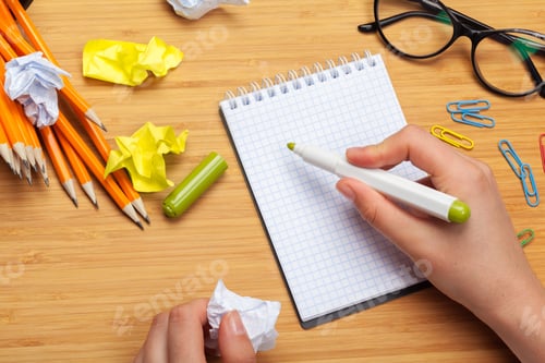 Preview: White note pad on a wooden table. Around the notepads lies lot crumpled paper