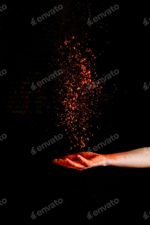 Preview: female hand with red colorful holi paint powder on black background