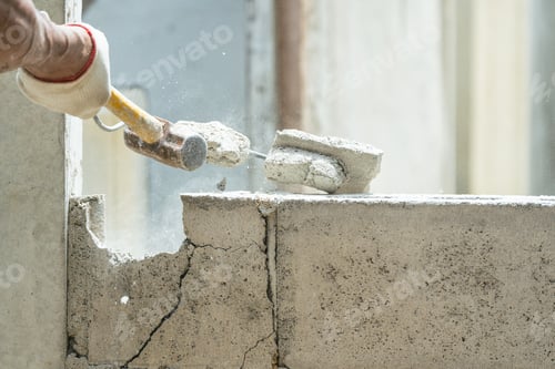 Preview: Hand of worker using hammer smashing and demolish on brick wall at construction site