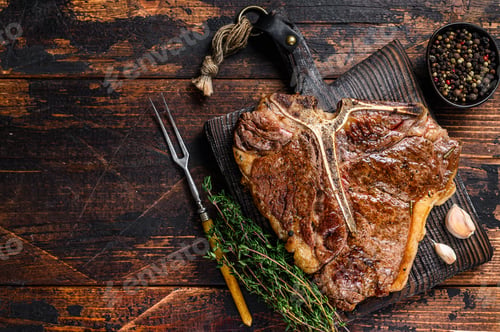 Preview: Roast t-bone or porterhouse beef meat Steak on a wooden cutting board. Dark wooden background.