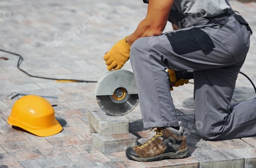Preview: Close up view. Male worker in yellow colored uniform have job with pavement