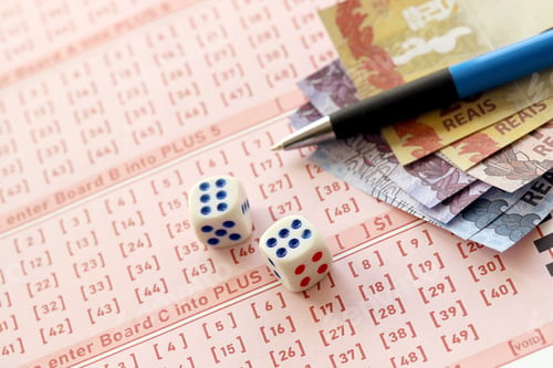 Preview: Dice cubes with Brazilian money bills on blank of lottery game