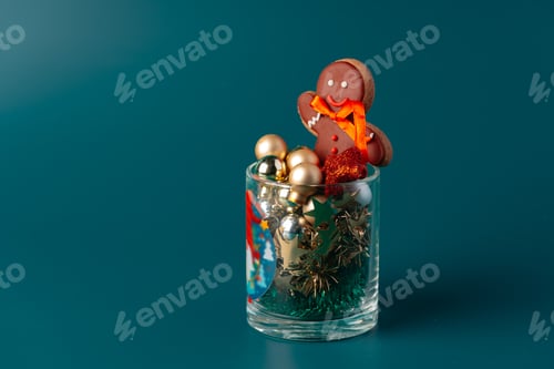 Preview: Glass with Christmas decorations on dark green background