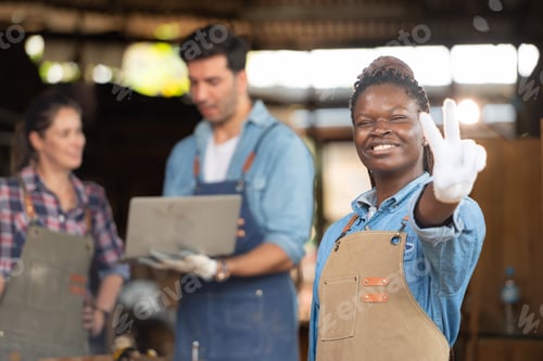 Preview: Portrait of carpenter female worker standing in front of colleague in workshop