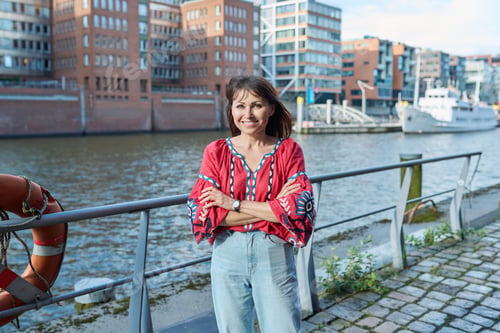 Preview: Mature smiling woman in embroidered shirt looking at camera, outdoor