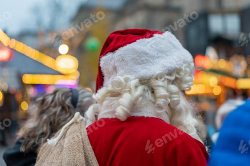 Preview: Closeup of the back of a Santa Claus with a sack standing in the street on a blurry background