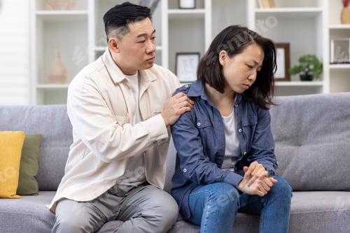 Preview: Family psychological support, Asian couple sitting at home on sofa thoughtful, woman comforting and