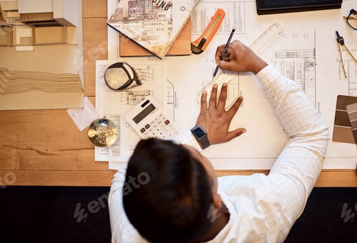 Preview: High angle shot of an architect using a ruler to draw a building plan
