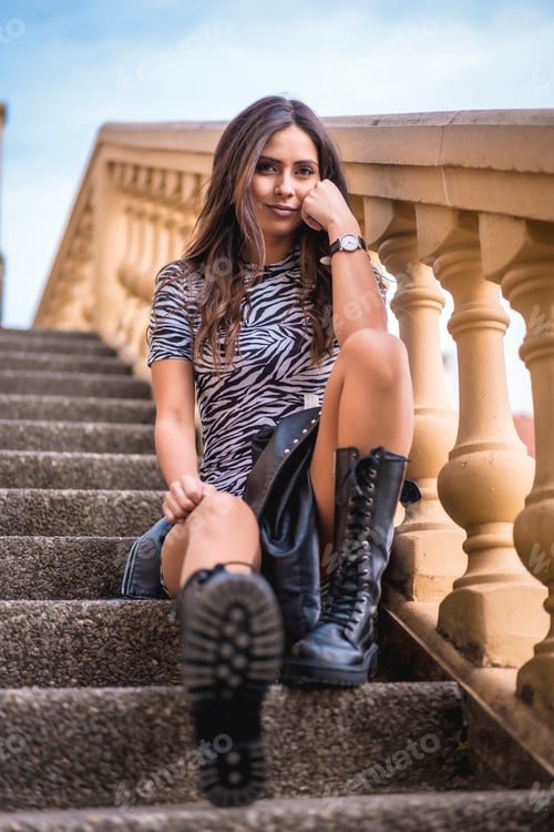 Preview: Lifestyle, look of a pretty brunette sitting on stairs with black boots