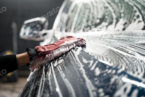 Preview: Professional car wash. Detailing worker washes the vehicle body with foam and rag