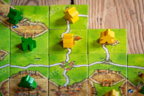 Preview: Carcassonne Board Game with tiles and meeples on wooden background.