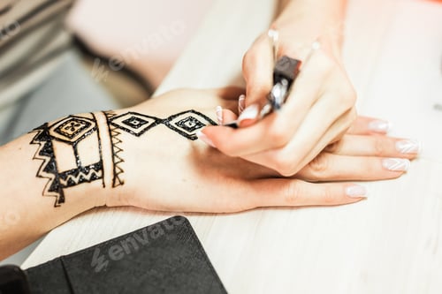 Preview: young woman mehendi artist painting henna on the hand