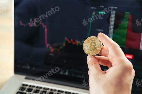 Preview: Crypto trader hands with golden bitcoin on background with financial chart data on laptop