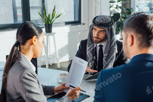 Preview: multicultural business partners discussing contract on meeting with professional translator in