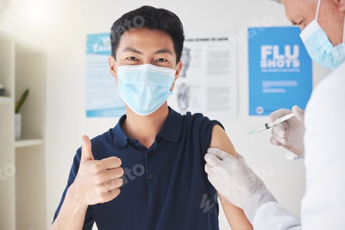 Preview: Shot of a young man showing a thumbs up while getting a vaccination at a hospital