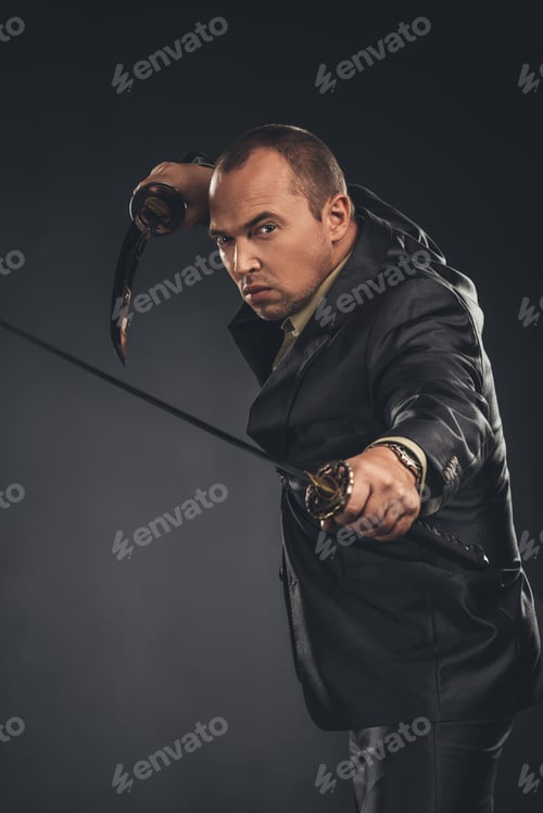 Preview: man in defence pose in suit with katana swords on black
