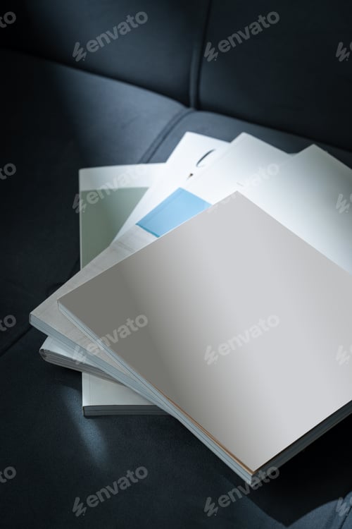 Preview: Stack of Magazines on a Black Leather Couch in Soft Light
