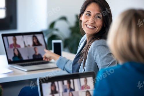 Preview: two business women speaking while doing a video call with diverse colleagues on online briefing