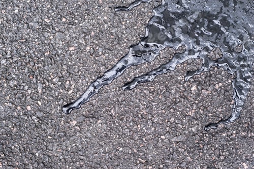 Preview: Black Wet Brilliant Glossy Bitumen Of An Abstract Form With Water Drops On Damp Speckled Asphalt