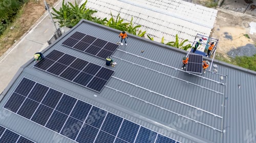 Preview: Solar panel installation on a rooftop with workers near agricultural area