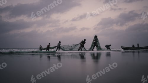 Preview: Group of fishers pulling their fishing net out of the sea after work at sunset