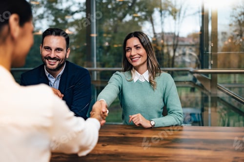Preview: Smiling businesswoman handshaking with a female client, sitting at the office, elegantly dressed.