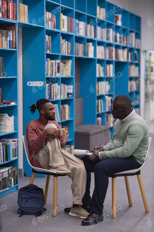 Preview: Young black student talking to therapist or guidance counselor in college