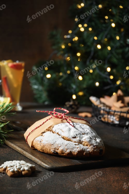 Preview: Christmas stollen on festive table with garland and evergreen branches.
