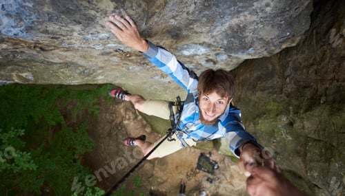 Preview: Young climber hanging on rope on rock. Man falling down from the cliff holding friend's hand