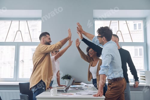 Preview: Group of confident young business people in smart casual wear holding hands together and smiling