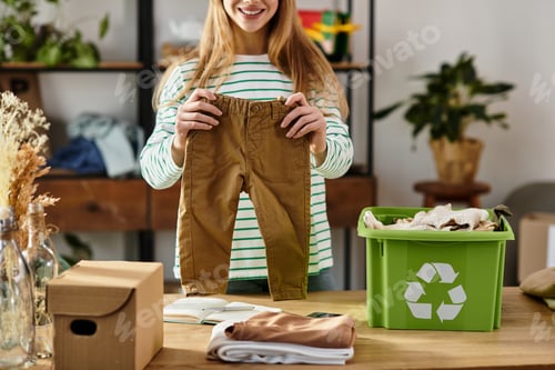 Preview: Young woman embraces sustainable fashion by sorting and recycling clothes at home
