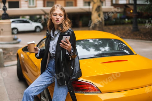 Preview: Young attractive woman in leather jacket leaning on yellow sport