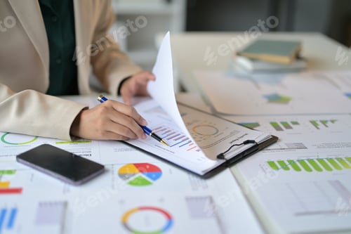Preview: Businesswoman analyzing financial data with charts and graphs at her office desk, using technology