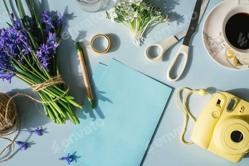 Preview: Sheets of paper, camera, scissors, cup of coffee and spring flowers on light blue background