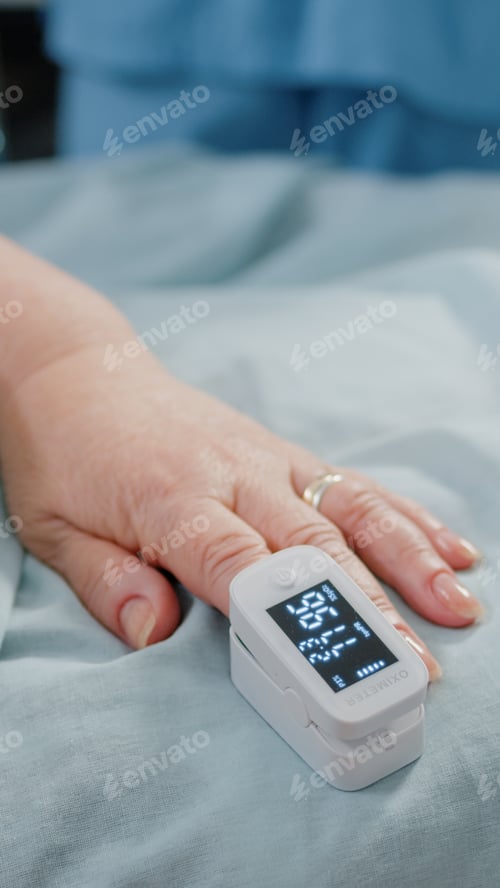 Preview: Close up of oximeter on hand of senior patient laying in bed