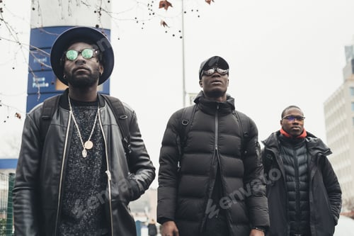 Preview: three young black men walking in the street and looking further