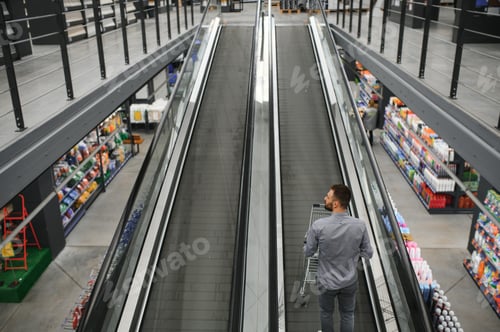 Preview: A man with a shopping cart on an escalator in a hardware store.