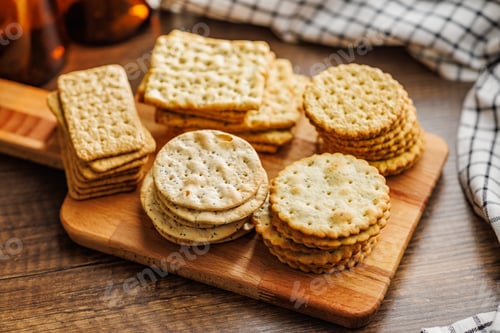 Preview: A stack of crackers neatly arranged on cutting board on wooden tabletop.