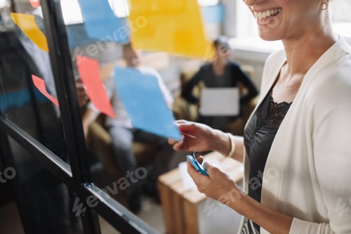 Preview: Smiling woman brainstorming using adhesive notes