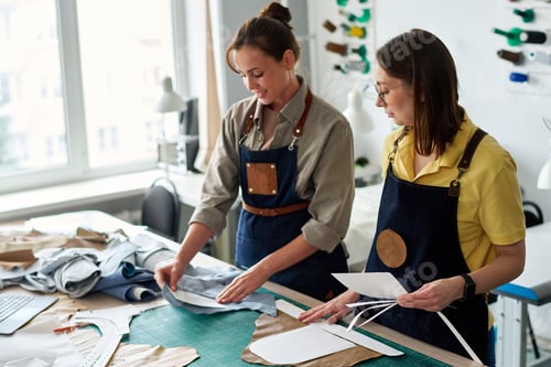 Preview: Young tailor holding sewing pattern on piece of blue leather