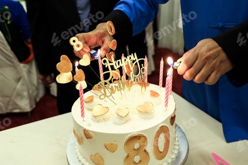 Vista previa: Primer plano de manos sosteniendo encendedores para encender velas en pastel de cumpleaños