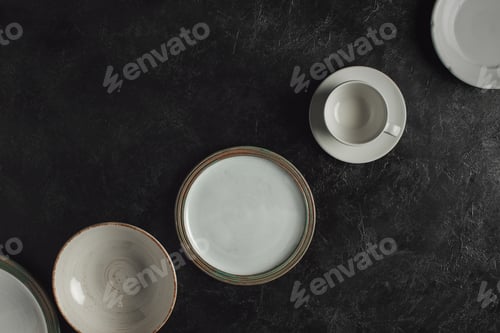 Preview: flat lay with ceramic plates and cup on saucer isolated on black table