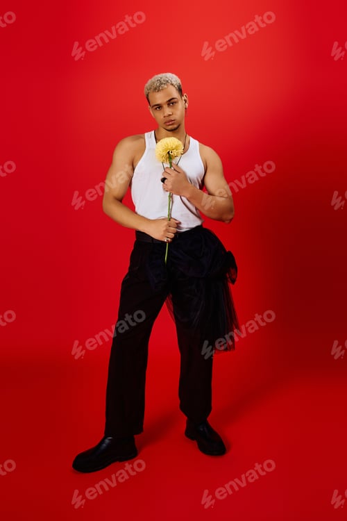Preview: A young man with dyed hair stands confidently, holding a flower in a vibrant studio
