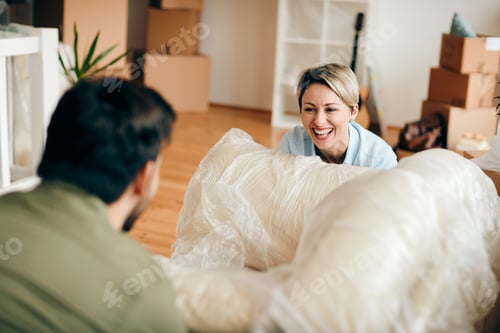 Preview: Cheerful woman having fun with her husband while moving into new apartment.
