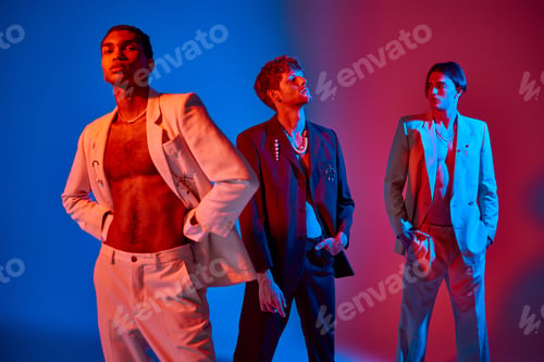 Preview: good looking elegant trio in classy suits with accessories with neon lights on faces, men power