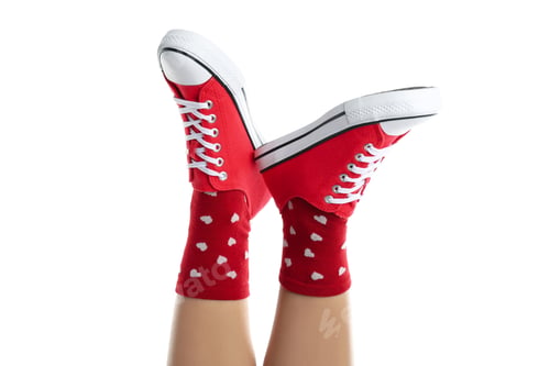 Preview: Female legs in socks with hearts and in sneakers isolated on white background