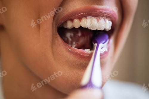 Preview: Close-up of unrecognizable woman brushing teeth.