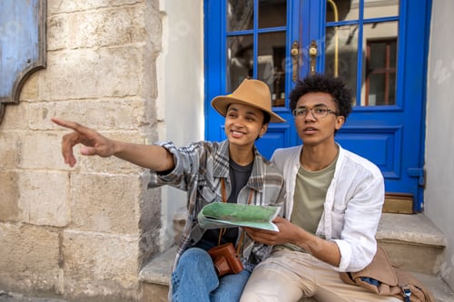 Preview: Discussing the route. Young couple sitting on the door step and discussing the route