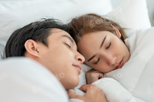 Preview: Asian attractive young couple lying down on bed to sleep in bedroom.