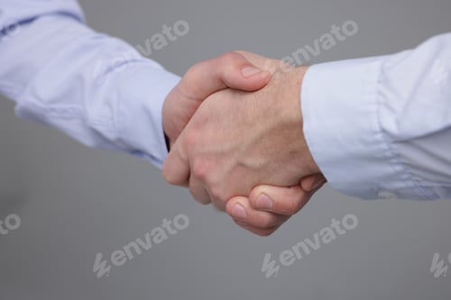 Preview: Businessmen shaking hands on grey background, closeup